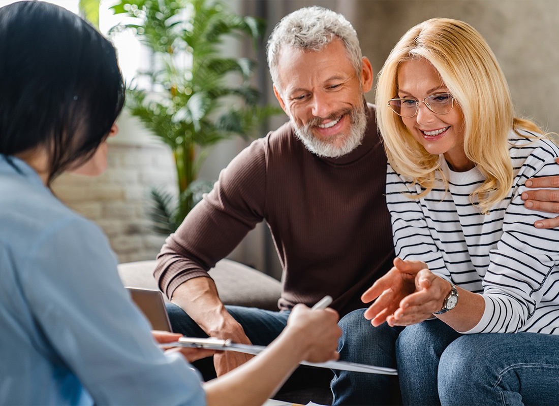 About Our Agency - Middle-Aged Couple Looking Over a Clipboard Together With an Agent